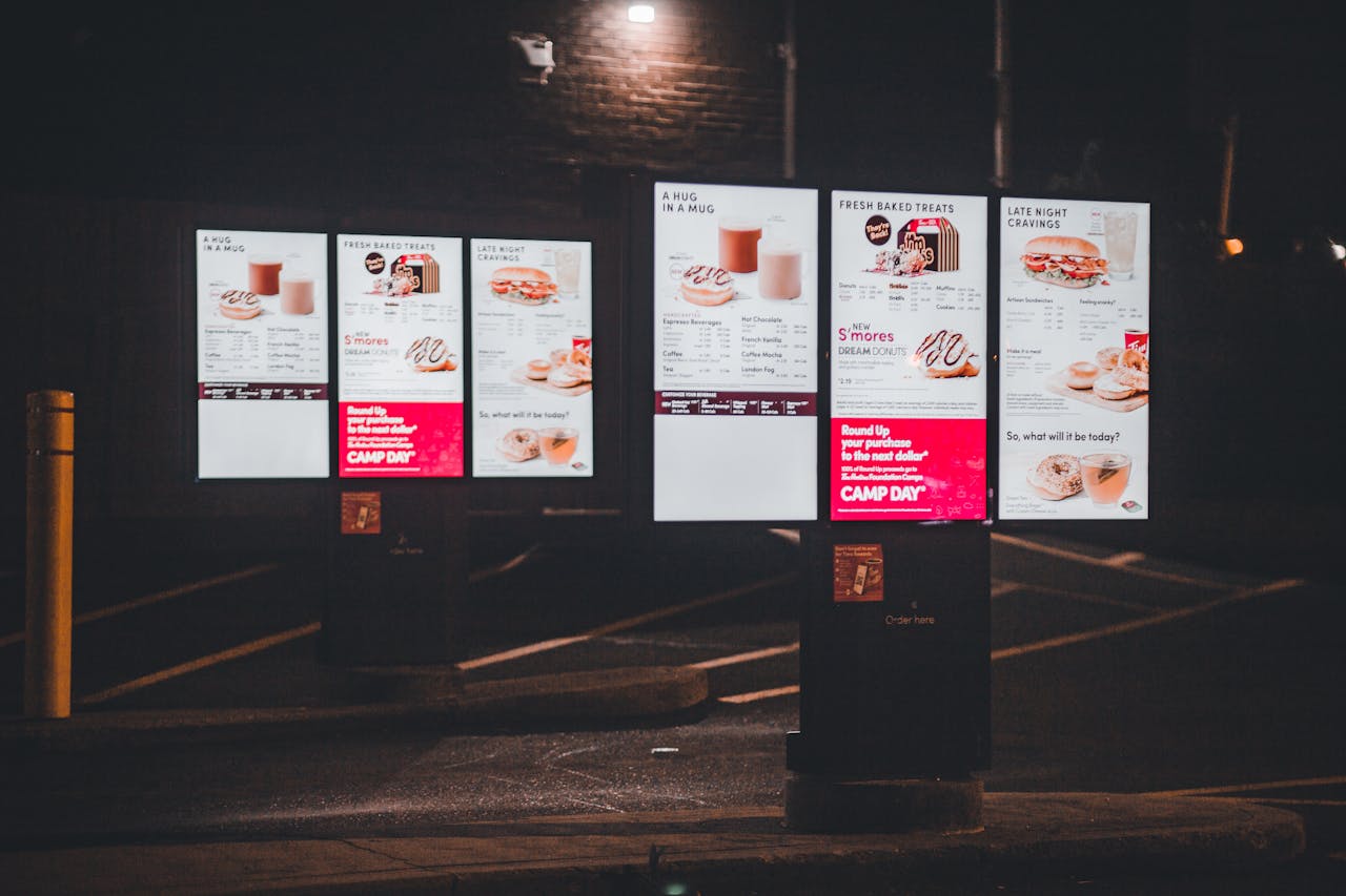 why-choose-us Nighttime view of an illuminated fast food drive-thru menu with digital display and clear copyspace.