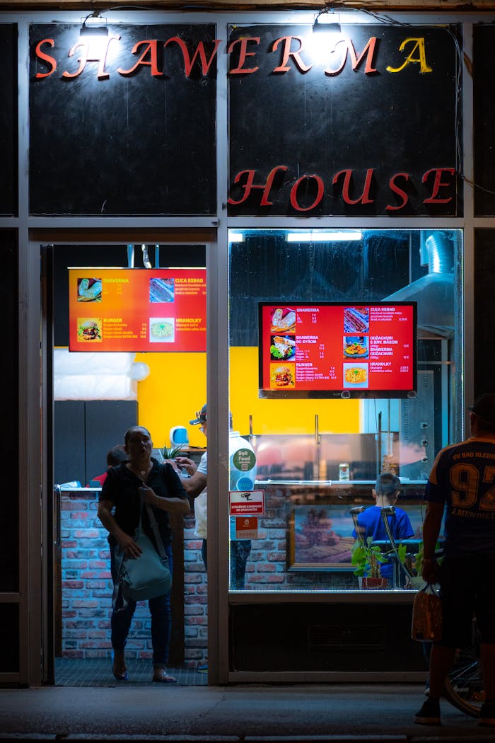 services-02 Nighttime exterior of Shawarma House with people visible inside.