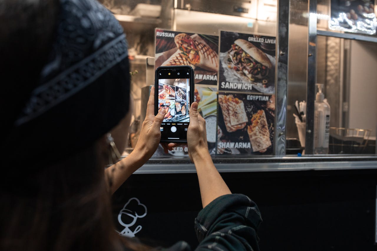 gallery-3 Photograph of a person taking a picture of a street food menu at night.